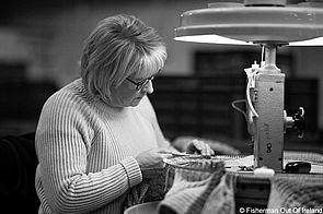 Eine Mitarbeiterin von Fisherman out of Ireland führt händisch Strickarbeiten an einem Kleidungsstück aus.