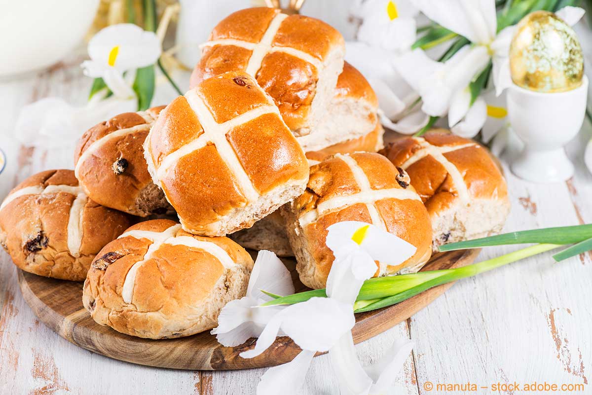 Gebackene Hot Cross Buns auf einem Holzbrett